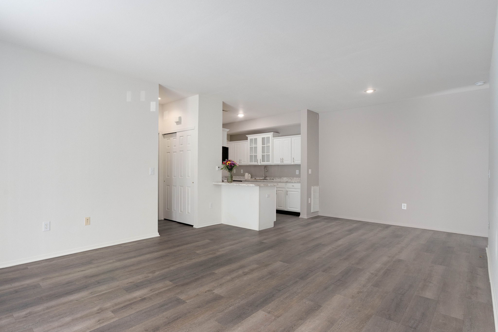 A spacious room with a kitchen in the background.